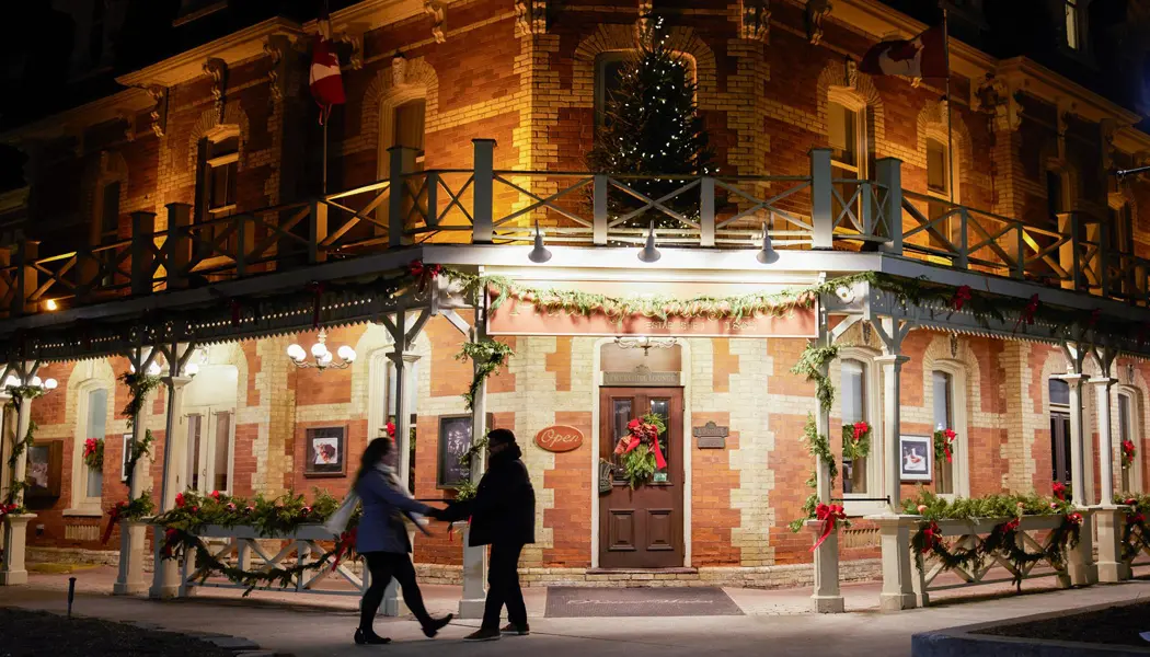 A couple holds hands in front of a romantic heritage inn in Niagara-on-the-Lake.