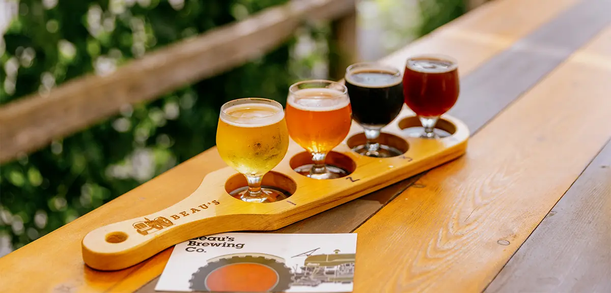 A selection of beers served with small dishes on a wooden tray.
