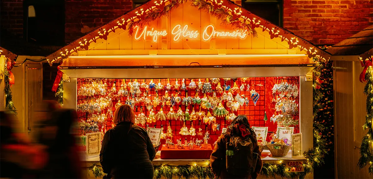Festive Christmas market stall decorated with garlands and colourful holiday ornaments at night.