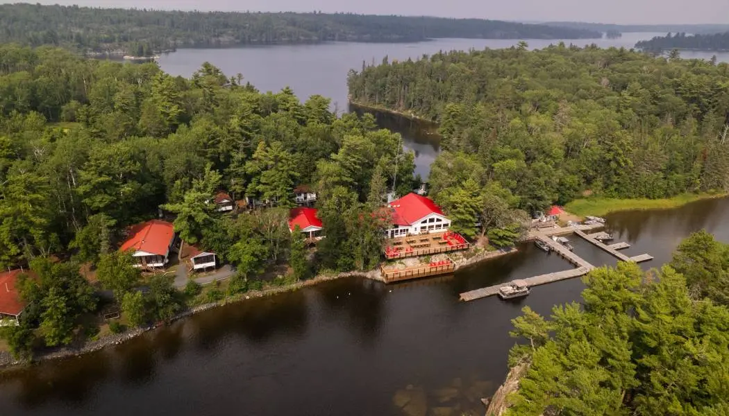 Vue aérienne d’un pavillon de pêche isolé dans le Nord de l’Ontario, accessible uniquement en bateau et entouré d’eau et de forêt.