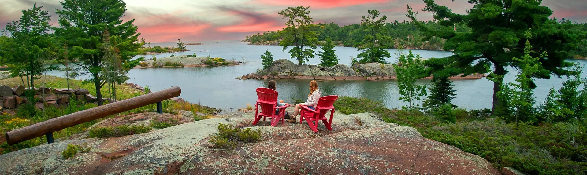 水を見渡す岩の上に赤いムスコカの椅子に座っている2人