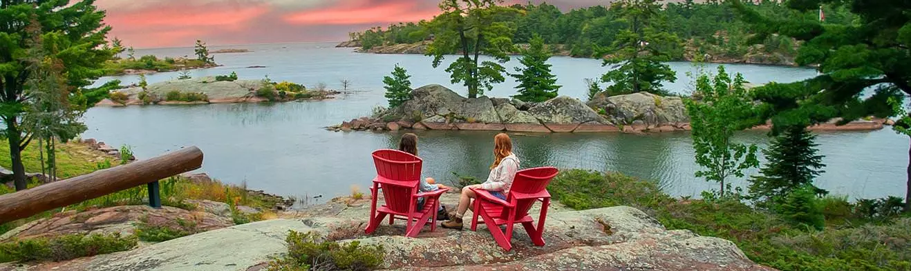 물이 내려다 보이는 바위에 빨간 무스코카의 자에 앉아 두 사람