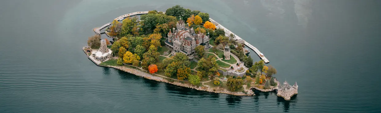 Vue aérienne du château de Boldt, à Alexandria Bay, avec ses tours de pierre, ses toits et ses arbres qui bordent le rivage, depuis les Mille-Îles.