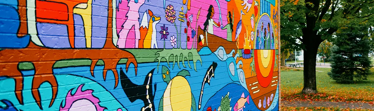 Ein Paar geht im Herbst an einem farbenfrohen Wandgemälde im Freien in der Nähe der Art Gallery of Algoma vorbei.