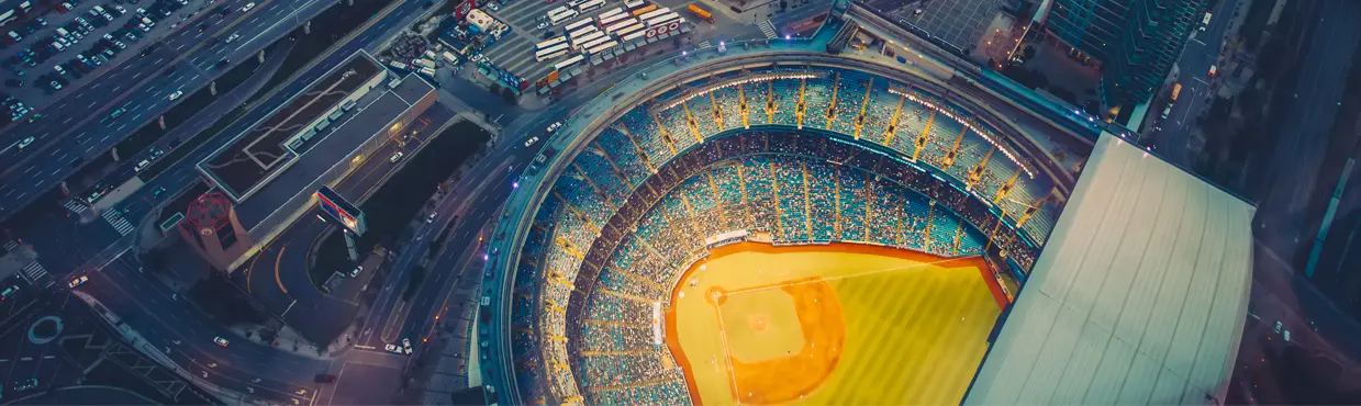 Luftaufnahme der Innenstadt von Toronto in der Abenddämmerung mit dem beleuchteten Rogers Centre-Stadion und der Uferpromenade und den Hochhäusern, die es umgeben.