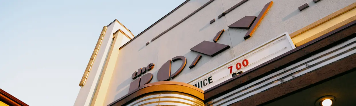 Exterior de color pastel del Teatro Roxy en Uxbridge con una marquesina de estilo retro que muestra títulos de películas actuales.