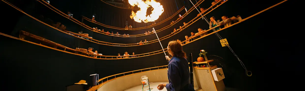 Un professeur de sciences fait une expérience sur le feu, sous le regard des visiteurs assis sur les gradins de Science Nord, à Sudbury, en Ontario.