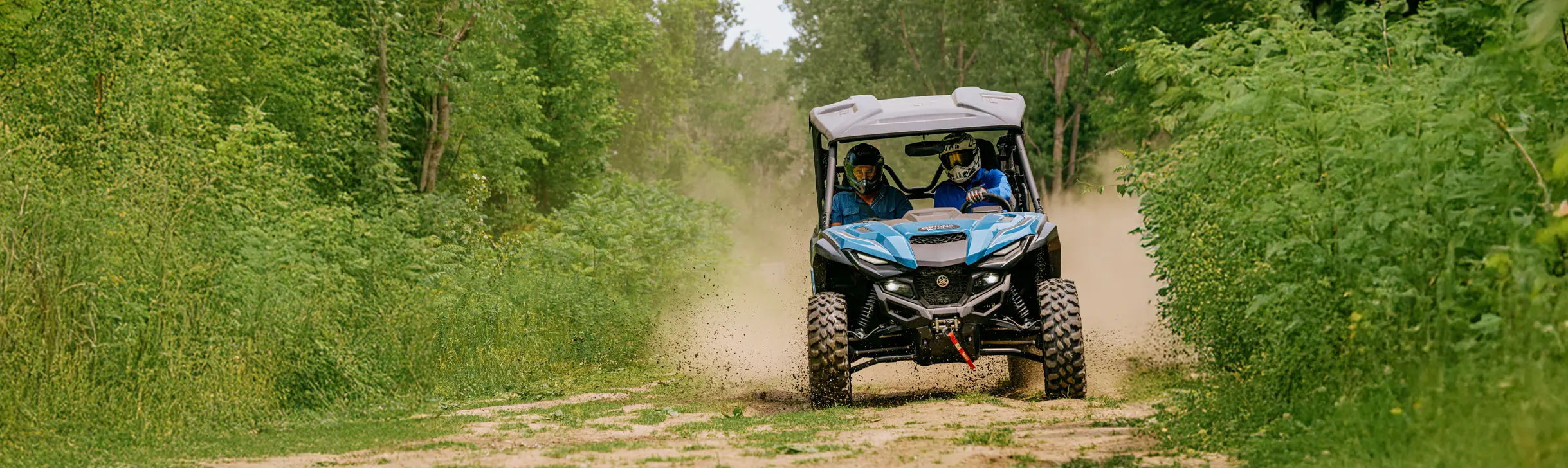 オンタリオ州ツイードの夏の日、森に囲まれた小道をATVに乗って走る人々。
