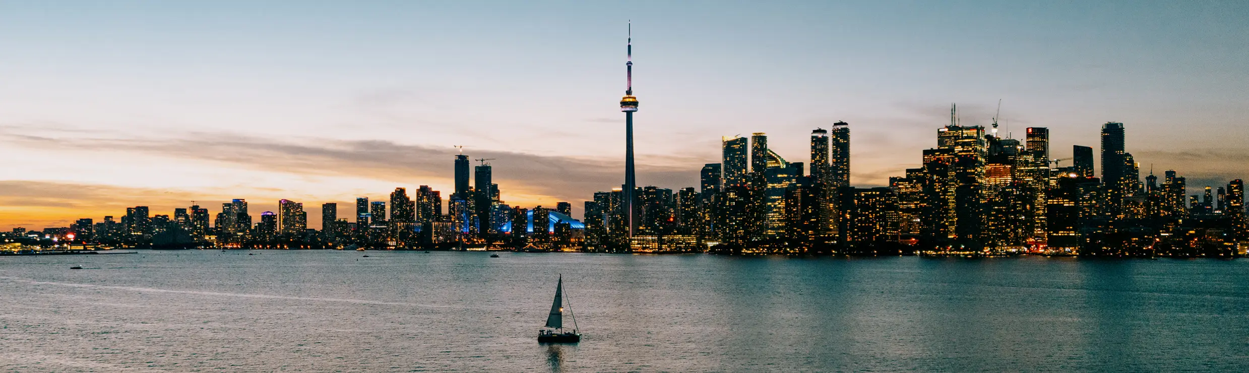 Silhouette de Toronto au coucher du soleil avec un bateau de luxe en train de naviguer.