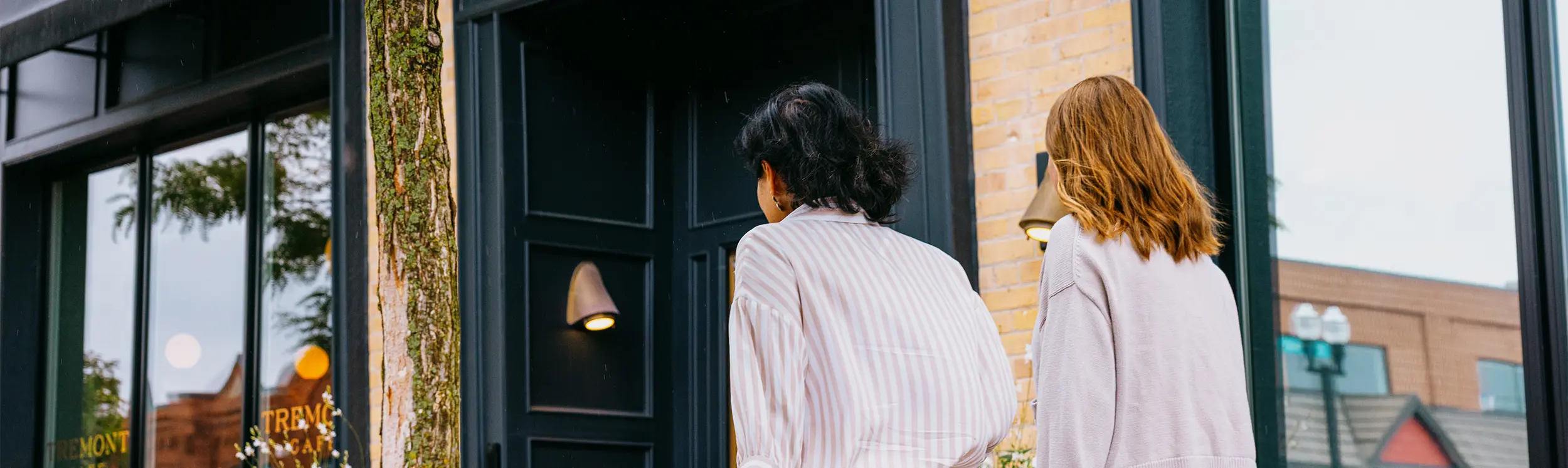 검은색 출입구와 벽돌 외관이 돋보이는 부티크 호텔로 들어서는 투숙객들.