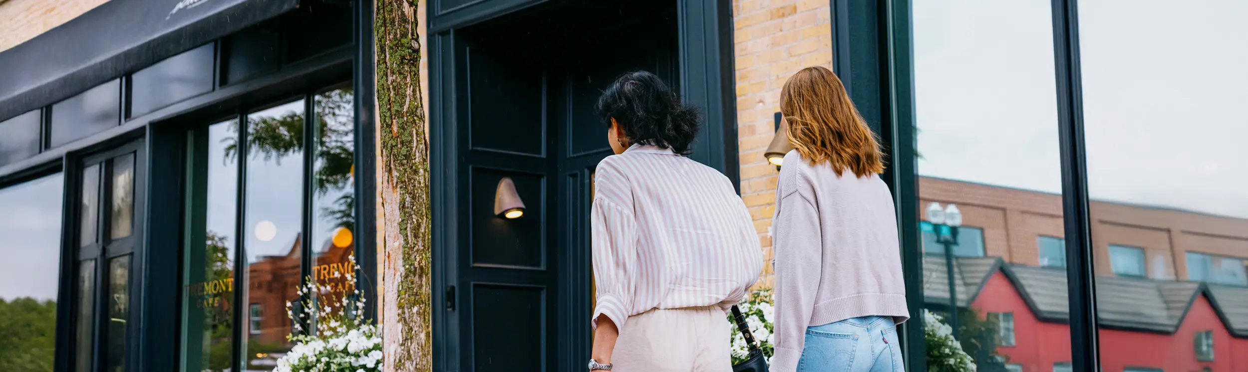 Guests entering a boutique hotel with a black doorway and brick exterior.