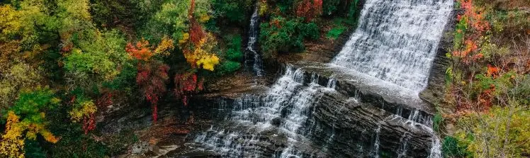 Overhead photo capturing a waterfall surrounded by fall colours. 