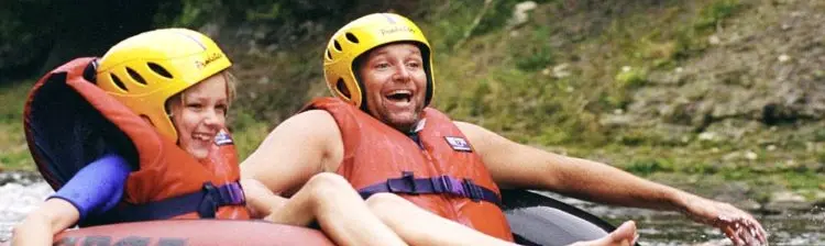 Un adulte et une enfant descendent une rivière en chambre à air en été.