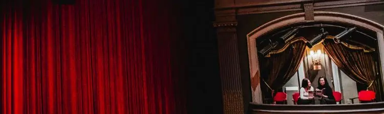 Deux femmes assises au balcon latéral, face au rideau et à la scène du Grand Theatre London.