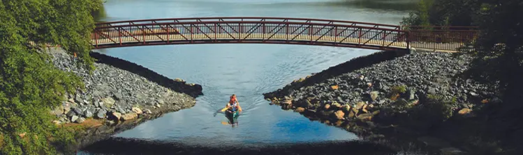 アローヘッド公園の歩道橋の下でカヌーを漕ぐ2人。