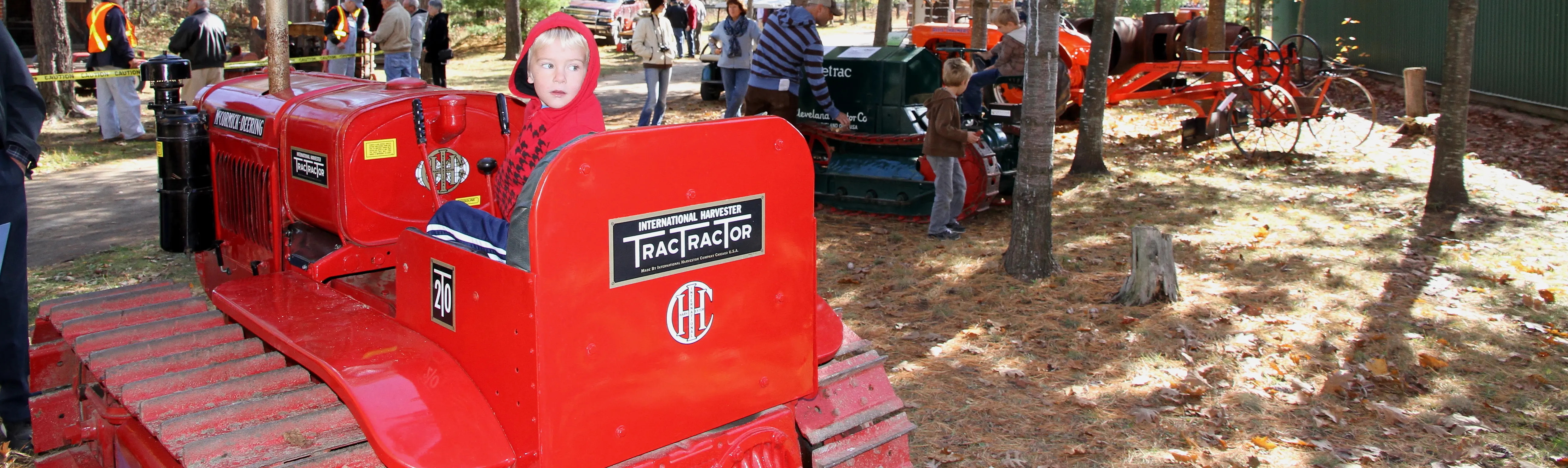 展示されているトラクターの上に子供が座っています。