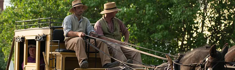衣装を着たスタッフが再現された 19 世紀の村で馬車に乗ります。