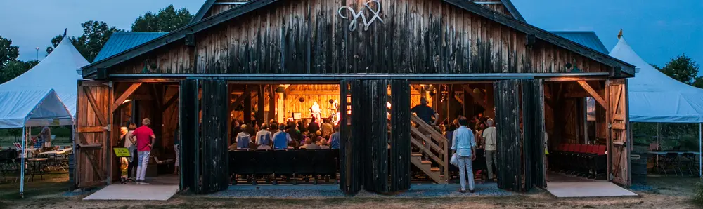 An audience gathers for a musical performance in a converted barn.