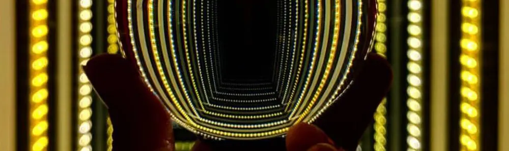 Die Hand einer Person hält einen Globus hoch, der Lichter reflektiert.