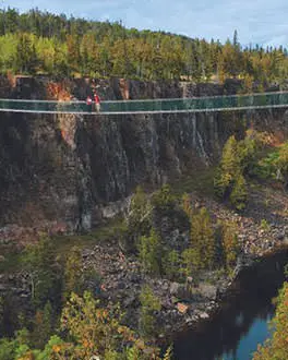 Ein Pärchen steht mitten auf einer Hängebrücke über eine weite Schlucht