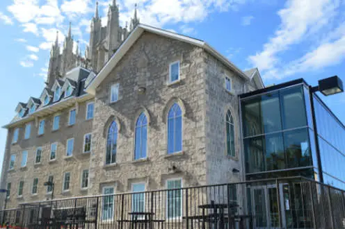 A large renovated stone convent with a large glass extension on the front of the building. 