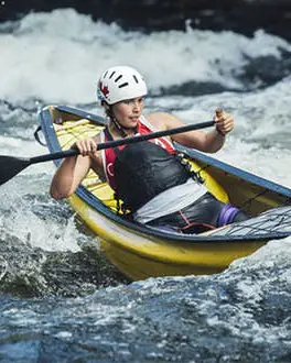A solo canoeist navigates whitewater rapids