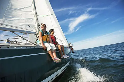 Profitant d'une journée ensoleillée, des marins s'assoient d'un côté de leur voilier