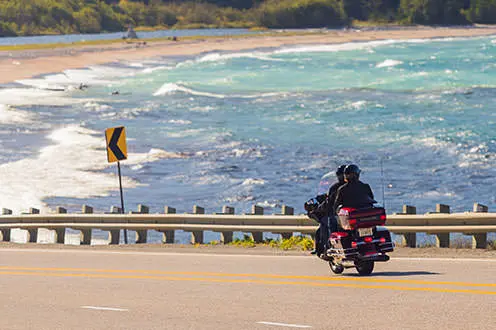 湖の隣の道路に沿って乗っているオートバイのカップル