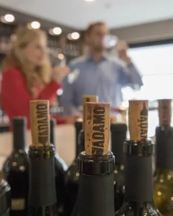 Bouchons sur des bouteilles de vin, tandis qu'un homme et une femme apprécient le vin en arrière-plan