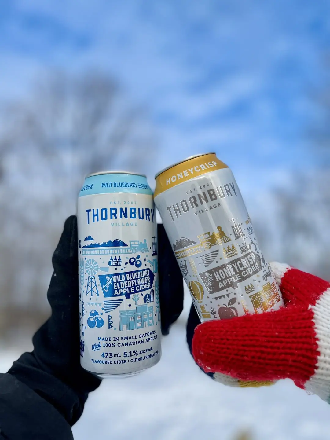 Two hands toasting cans of cider. 