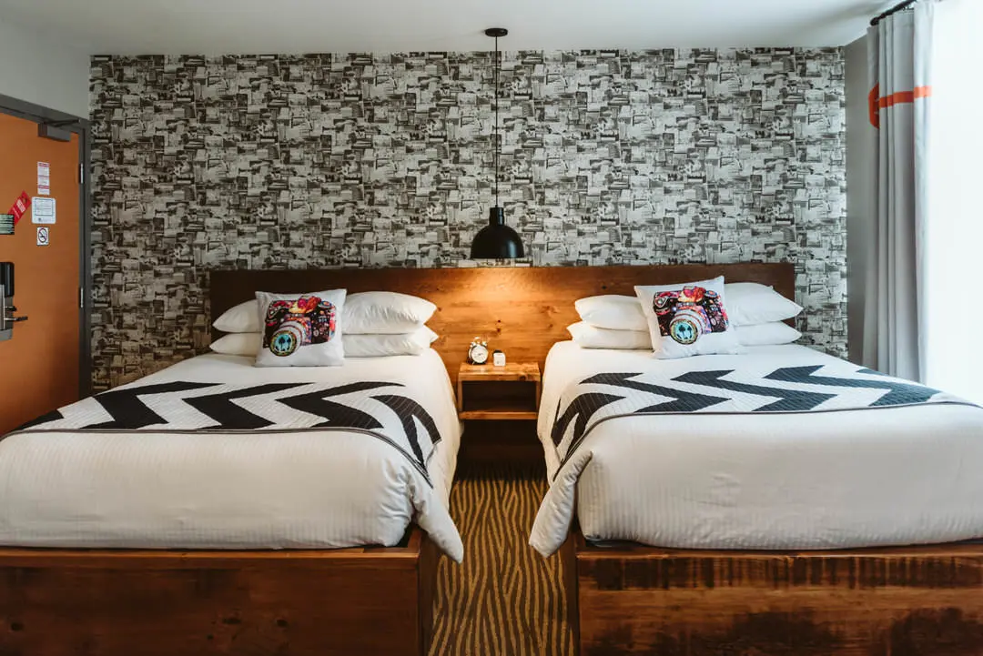 La literie et l'éclairage doux mettent en valeur le mur d'accent dans une chambre d'hôtel de charme