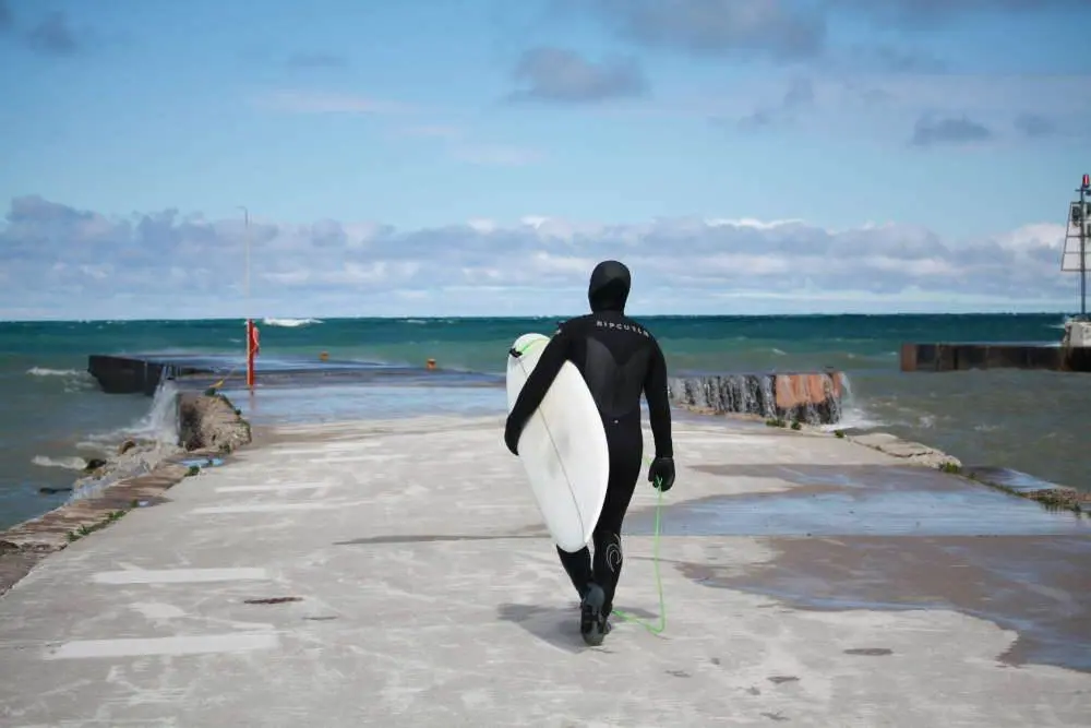 Surfer tenant une planche de surf marchant vers un lac