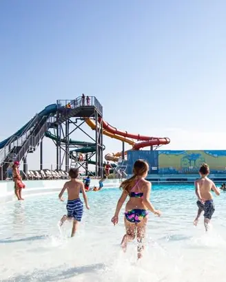 Los niños en traje de baño se divierten en la piscina mientras los socorristas los vigilan.