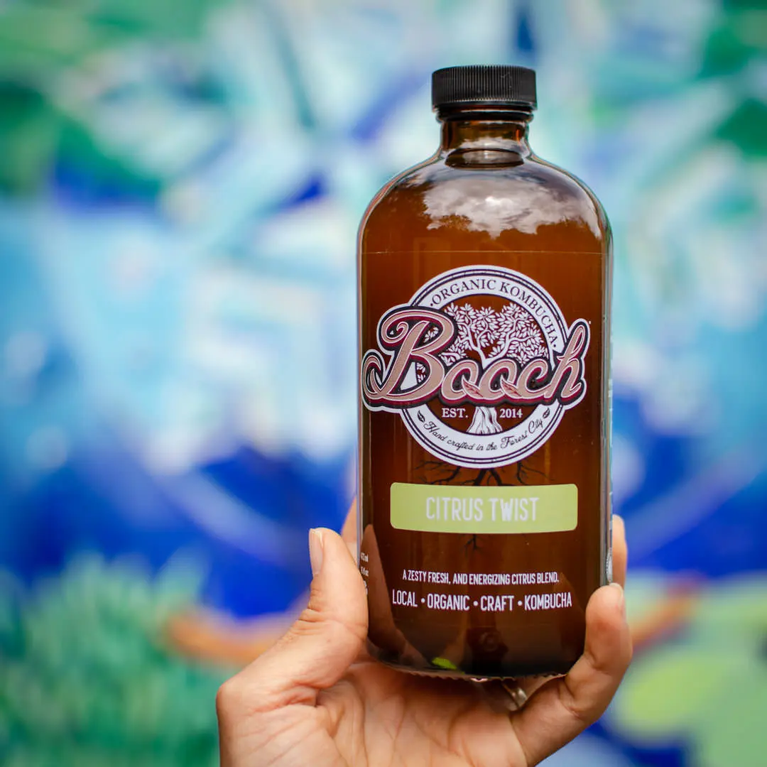 Mano sujetando una botella de Booch con la etiqueta Citrus Twist
