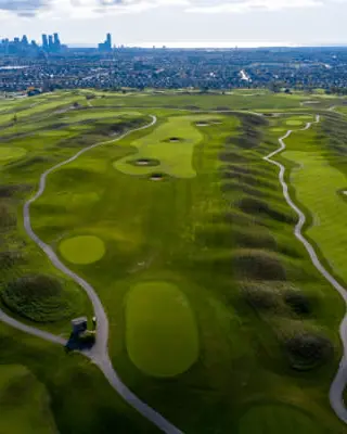 Aerial view of green grass with elevations and holes and sand traps and and pathways