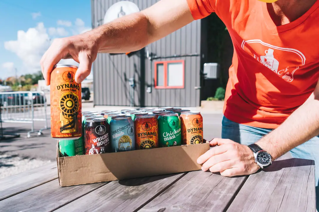 Gentleman packing cans of various kinds of beer outside brewery building