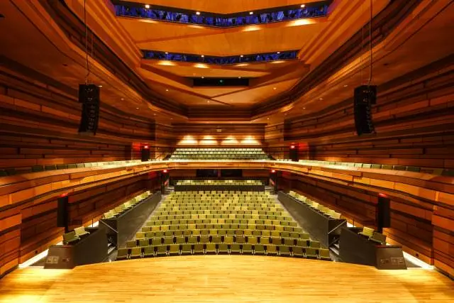 Konzertsaalbühne mit Blick auf die Sitzreihen im Fond mit geschnitzter Holzdecke mit gedämpfter Beleuchtung