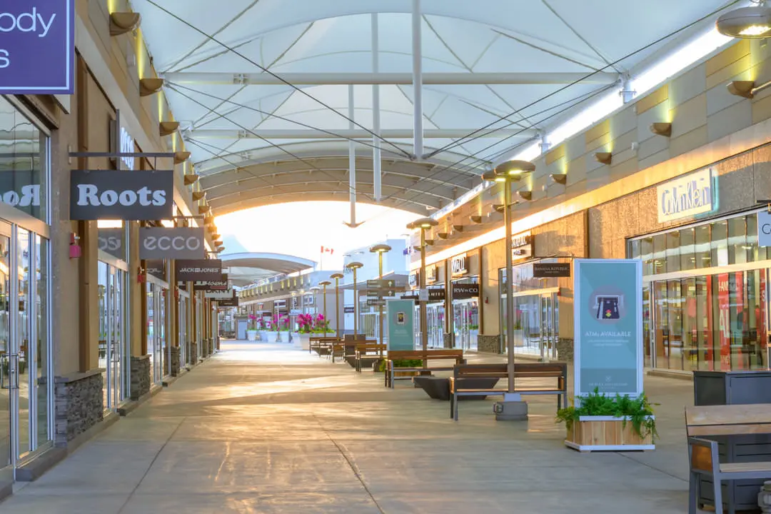 Très long centre commercial intérieur avec rangée de bancs au milieu d'une allée et de nombreux magasins de chaque côté qui disparaissent au loin.