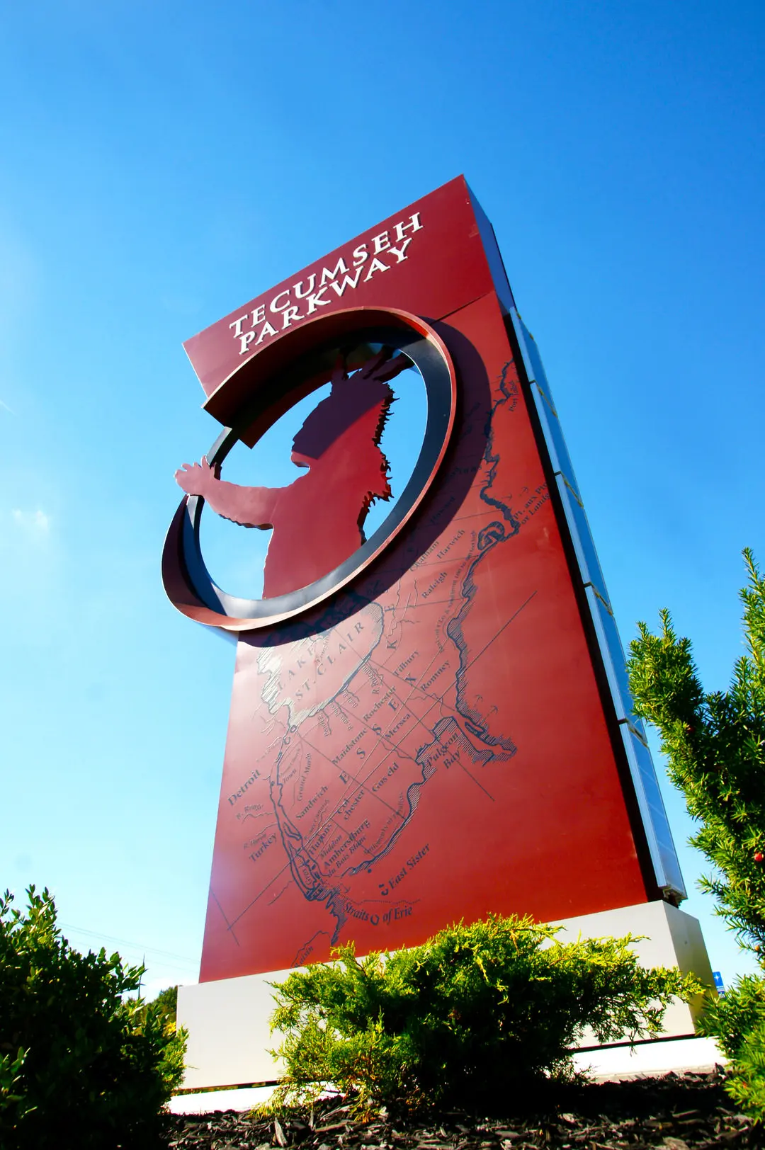 Enormous red sign showing township map and with circle cut out at top around sculpted outline of native chief with headdress