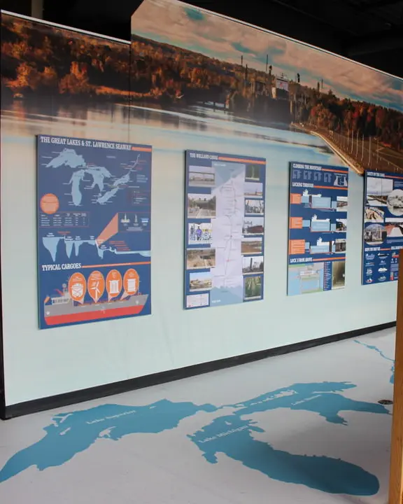 En la pantalla del tamaño de la pared izquierda de mapas y fotos y en la foto grande de la derecha del barco en la esclusa sobre un modelo a escala de la instalación de la esclusa