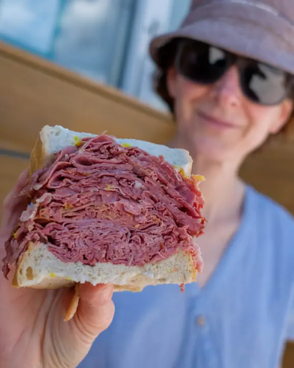Woman displaying her meat sandwich to the camera