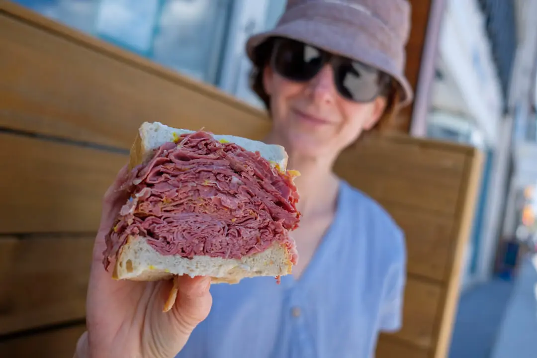 Mujer mostrando su sándwich de carne a la cámara.