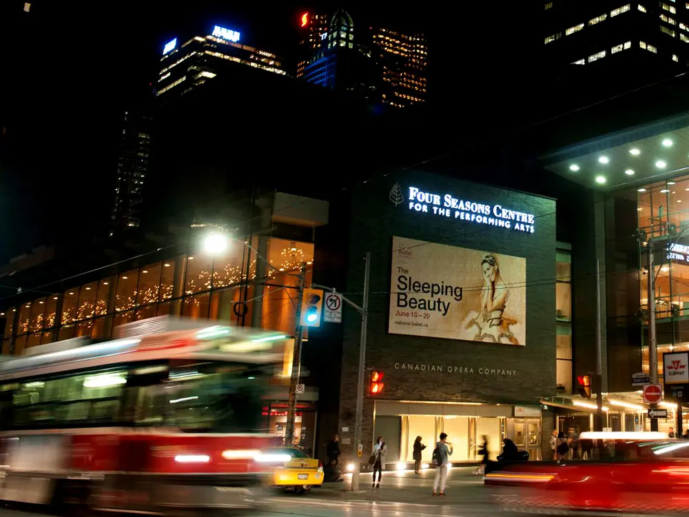 Un tramway et la circulation passent devant une grande affiche pour le ballet de la Belle au bois dormant à Toronto