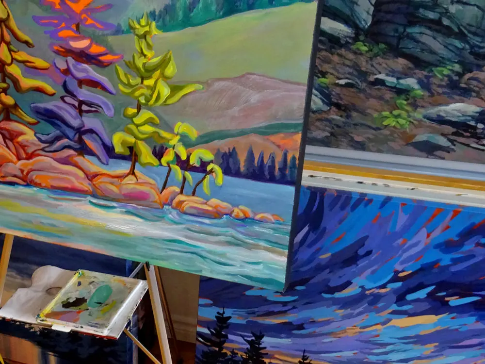 The work station of a local artist featuring a colourful landscape painting.