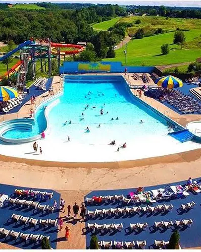 Bird's eye view of people enjoying a large wave pool, surrounded by lounge chairs and two blue and yellow umbrellas