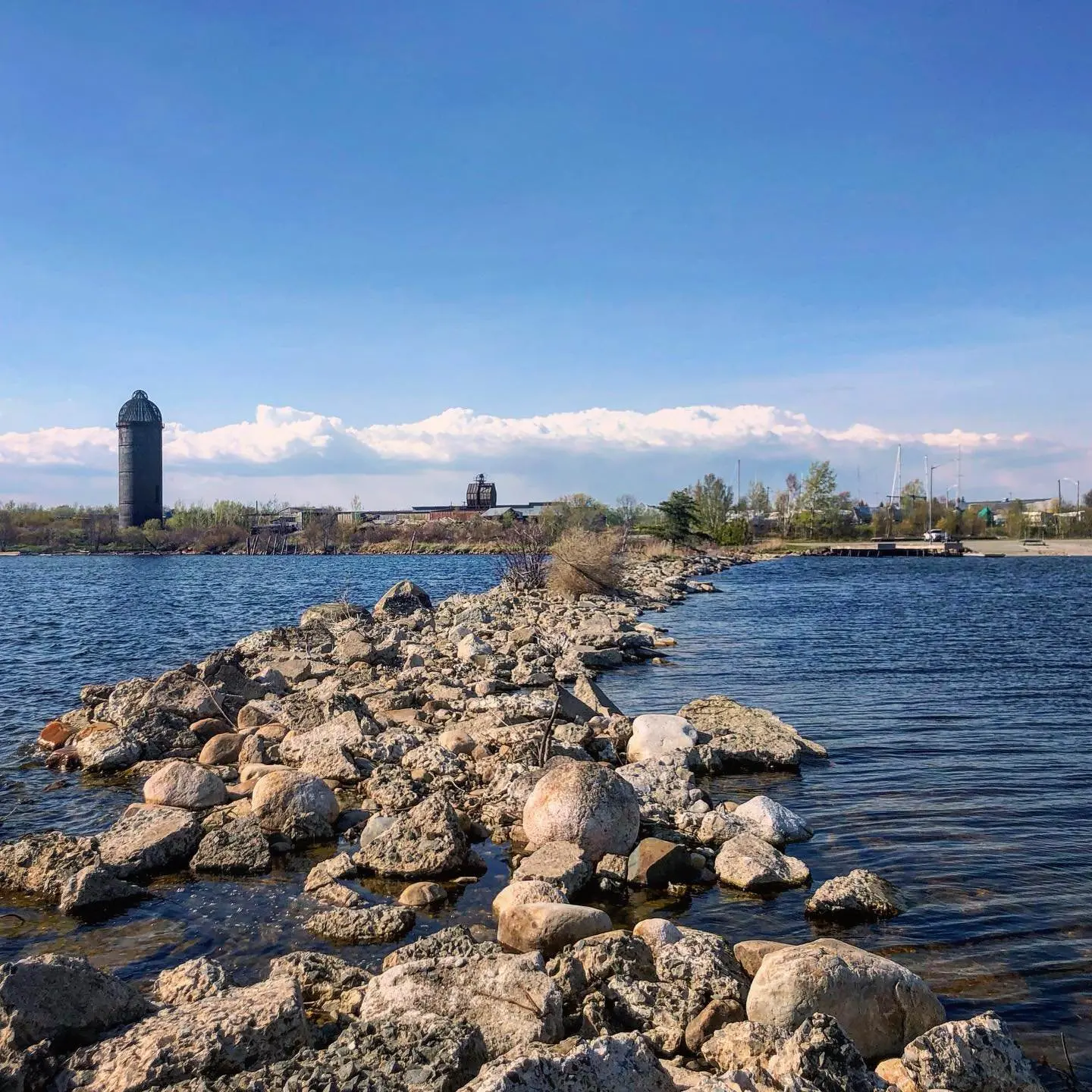 Du point de vue de se tenir sur une péninsule rocheuse entourée d'eau en regardant la marina sur le rivage
