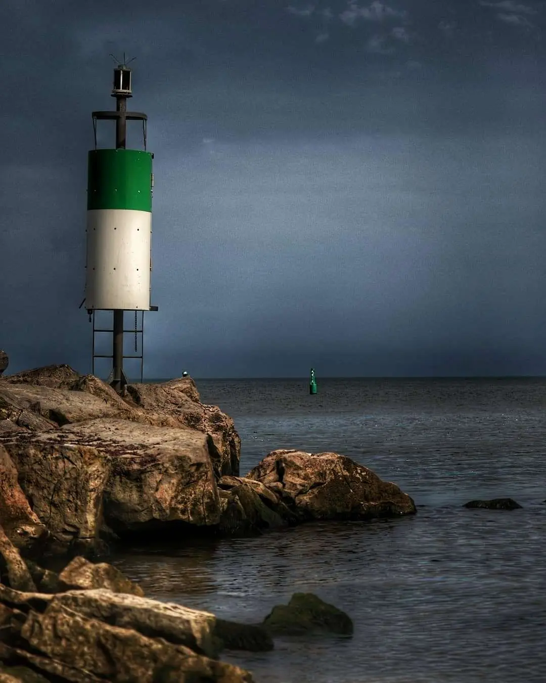 Un ciel sombre sur le lac avec un littoral rocheux doté d'un système d'avertissement lumineux pour les bateaux