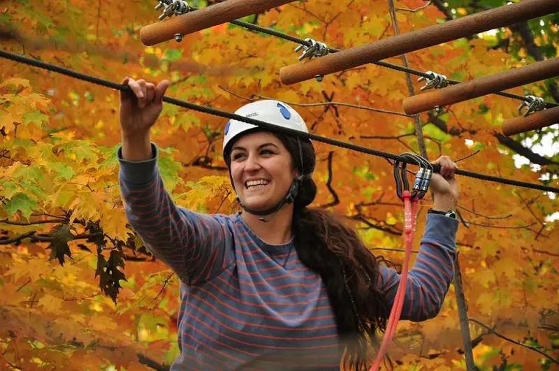 Une femme souriante faisant de la tyrolienne dans une forêt 