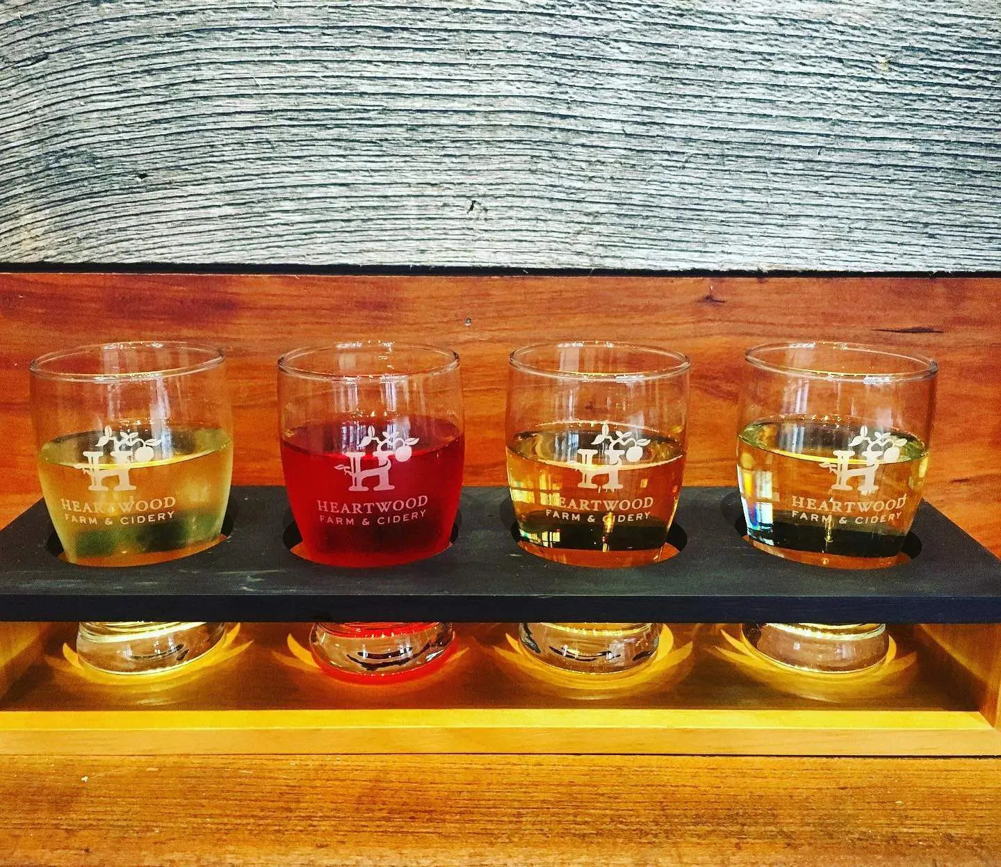 A flight of 4 ciders sitting on a wood table