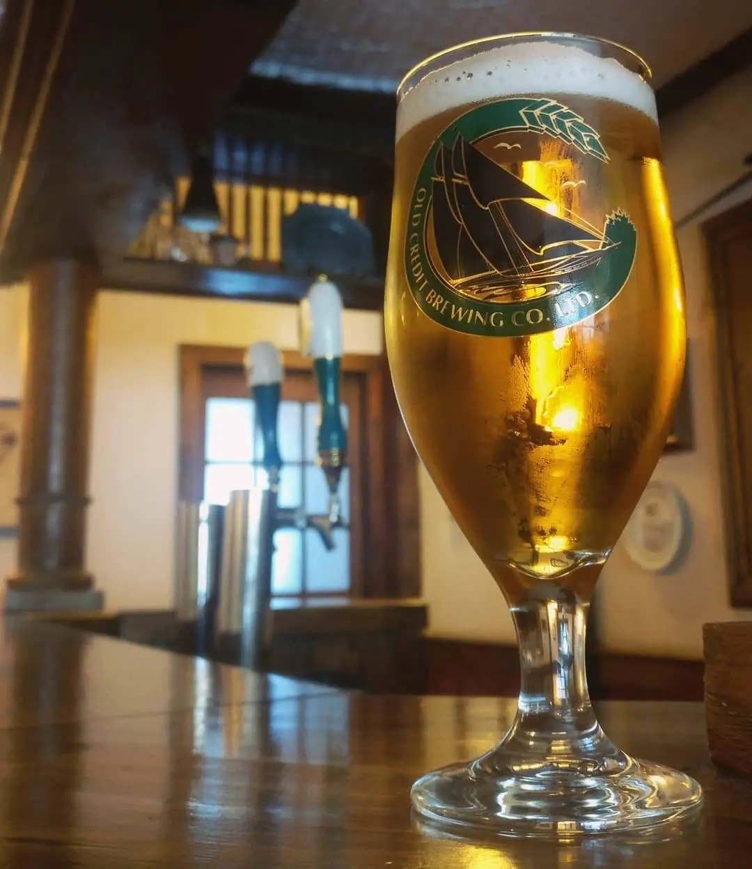 A close up of an Amber beer, with beer taps in the background